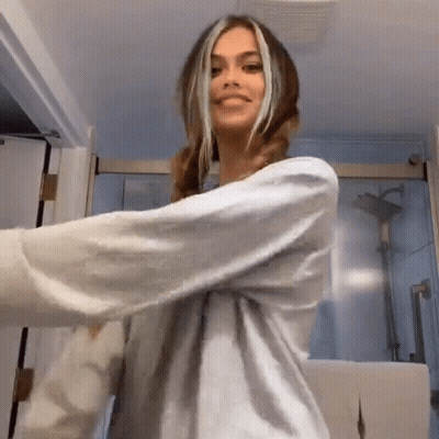 A Woman In A White Shirt Is Dancing In A Bathroom . GIF