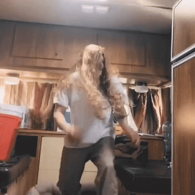A Woman In A White Shirt Is Dancing In A Kitchen GIF