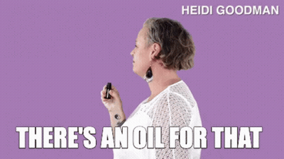 A Woman In A White Shirt Is Holding A Bottle Of Oil . GIF