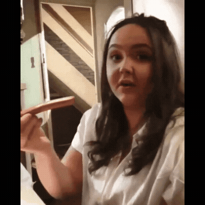 A Woman In A White Shirt Is Holding A Sausage In Her Hand GIF
