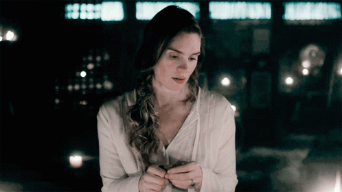 A Woman In A White Shirt Is Holding Something In Her Hands GIF