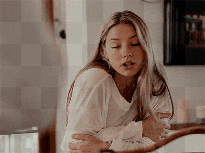 A Woman In A White Shirt Is Hugging Another Woman GIF