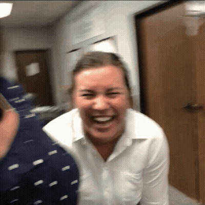 A Woman In A White Shirt Is Laughing With A Man In A Blue Shirt GIF