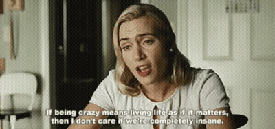 A Woman In A White Shirt Is Sitting At A Table With A Quote On It . GIF