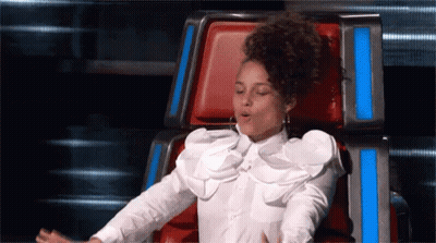 A Woman In A White Shirt Is Sitting In A Chair With Her Mouth Open GIF