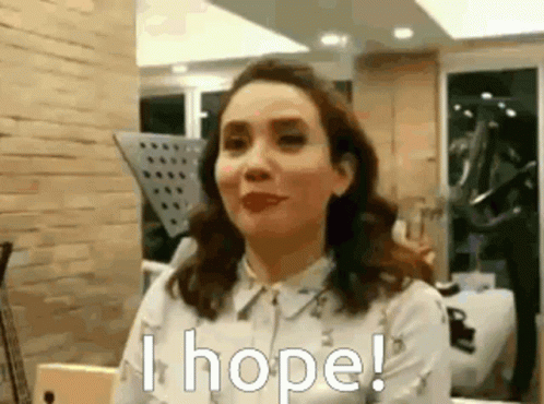 A Woman In A White Shirt Is Sitting In A Room And Says `` I Hope '' . GIF