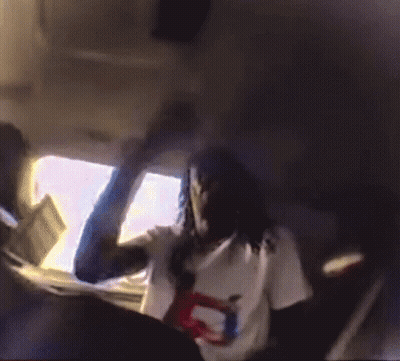 A Woman In A White Shirt Is Sitting In The Back Seat Of A Car Holding A Doll . GIF