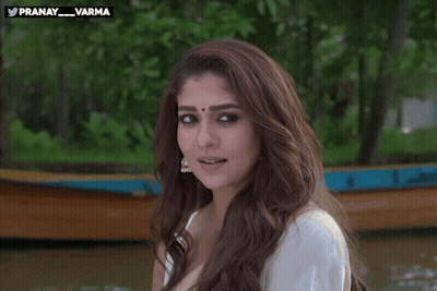 A Woman In A White Shirt Is Smiling And Waving In Front Of A Boat With The Hashtag Pranay_varma GIF