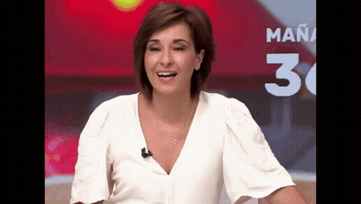 A Woman In A White Shirt Is Smiling In Front Of A Sign That Says Mañana GIF
