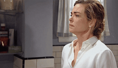 A Woman In A White Shirt Is Standing In A Bathroom Looking Down GIF