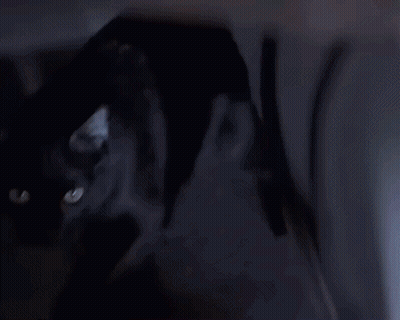 A Woman In A White Shirt Is Standing In A Dark Room . GIF