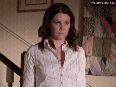 A Woman In A White Shirt Is Standing In Front Of A Quilt That Says Dr Pflaumisen GIF