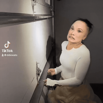 A Woman In A White Shirt Is Standing In Front Of A Wall With A Tiktok Watermark GIF