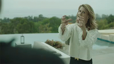 A Woman In A White Shirt Is Standing On A Balcony With Her Arms Outstretched . GIF