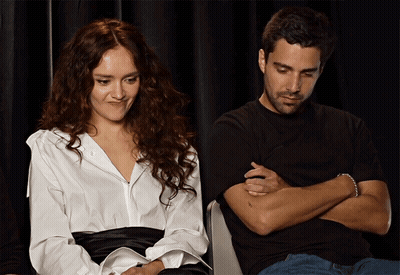 A Woman In A White Shirt Sits Next To A Man In A Black Shirt GIF