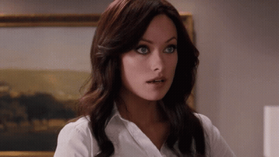 A Woman In A White Shirt Stands In Front Of A Framed Painting GIF