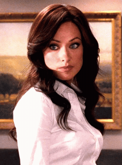 A Woman In A White Shirt Stands In Front Of A Framed Painting GIF