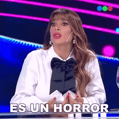 A Woman In A White Shirt With A Black Bow Tie Is Sitting At A Table Saying Es Un Horror GIF
