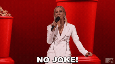 A Woman In A White Suit Is Holding A Microphone And Says " No Joke " GIF