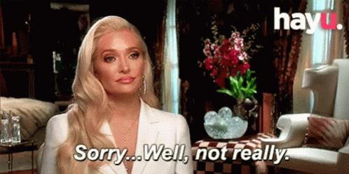 A Woman In A White Suit Is Sitting In A Living Room . GIF