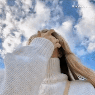 A Woman In A White Sweater Covering Her Face Against A Blue Sky GIF