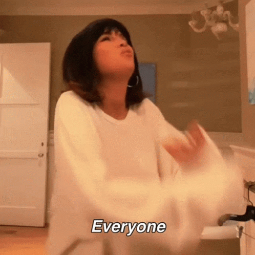 A Woman In A White Sweater Is Dancing In A Room With The Words Everyone Above Her Head GIF