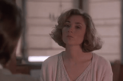 A Woman In A White Sweater Is Looking At A Man In A Room . GIF