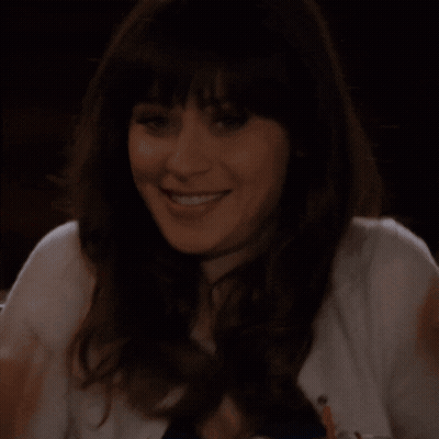 A Woman In A White Sweater Is Smiling With Her Hands On Her Chin GIF
