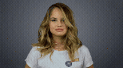 A Woman In A White T-Shirt Is Holding A Lollipop And Making A Funny Face . GIF