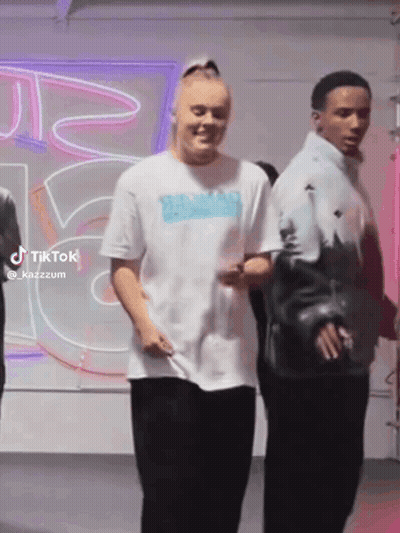 A Woman In A White T-Shirt Is Standing Next To A Man In A Blue Jacket . GIF