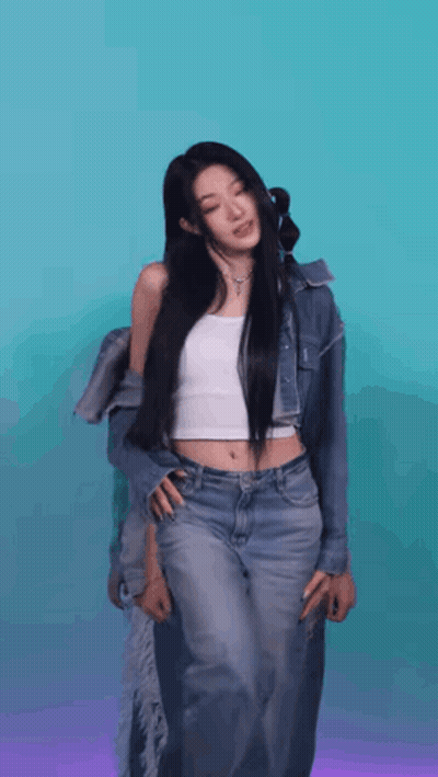 A Woman In A White Tank Top And Jeans Is Standing In Front Of A Blue And Purple Background . GIF