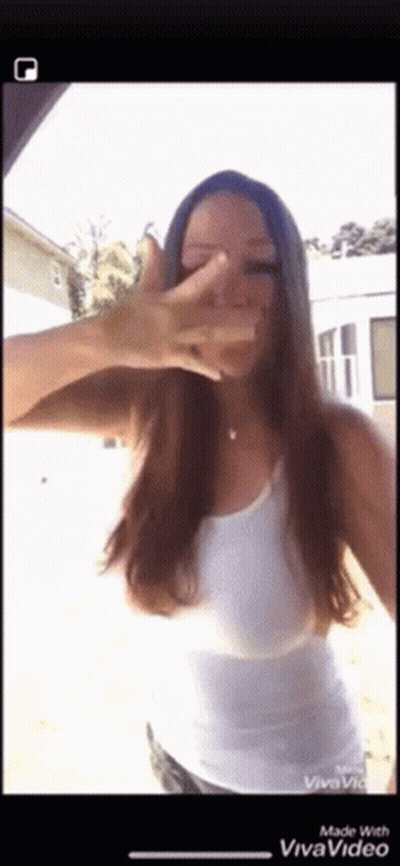 A Woman In A White Tank Top Covering Her Face With Her Hand GIF
