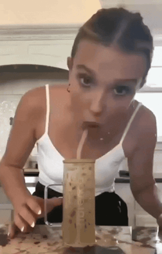 A Woman In A White Tank Top Drinks Through A Straw From A Cup That Says Mcdonald 'S On It GIF