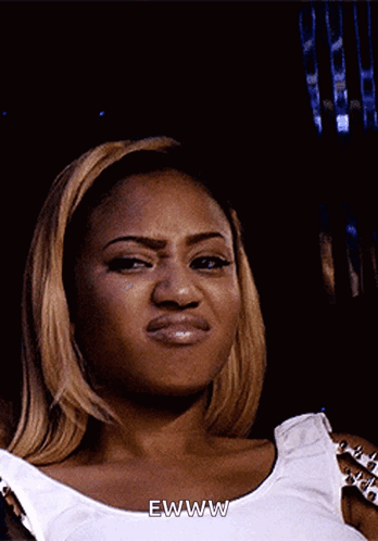 A Woman In A White Tank Top Says Ewww On Her Face GIF