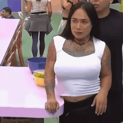 A Woman In A White Tank Top Stands Next To A Man GIF