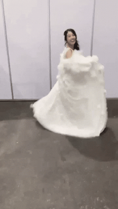 A Woman In A White Wedding Dress Is Dancing On A Floor . GIF
