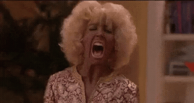 A Woman In A Wig Is Screaming With Her Mouth Open . GIF