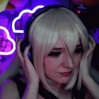 A Woman In A Wig Is Wearing Headphones In Front Of A Purple Neon Sign . GIF