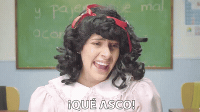 A Woman In A Wig Says Ique Asco In Front Of A Green Board GIF