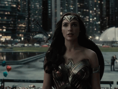 A Woman In A Wonder Woman Costume Holds A Sword And Shield GIF