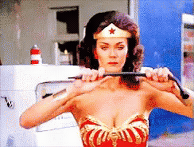A Woman In A Wonder Woman Costume Is Holding A Whip In Her Hands GIF