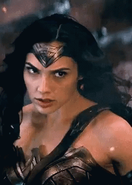 A Woman In A Wonder Woman Costume Is Looking At The Camera GIF