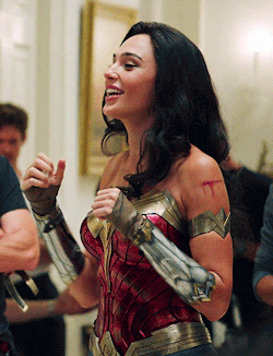 A Woman In A Wonder Woman Costume Is Smiling While Standing In A Room GIF