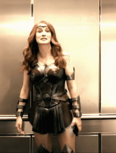 A Woman In A Wonder Woman Costume Is Standing In A Elevator GIF