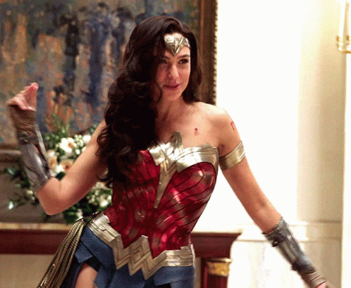 A Woman In A Wonder Woman Costume Is Standing In Front Of A Fireplace GIF