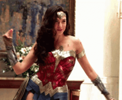 A Woman In A Wonder Woman Costume Is Standing In Front Of A Painting . GIF