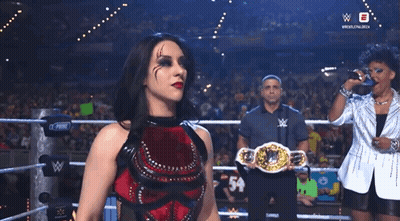 A Woman In A Wrestling Ring Holding A Belt That Says ' W ' On It GIF