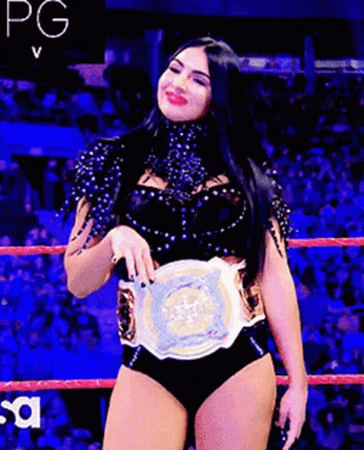 A Woman In A Wrestling Ring Holding A Championship Belt GIF