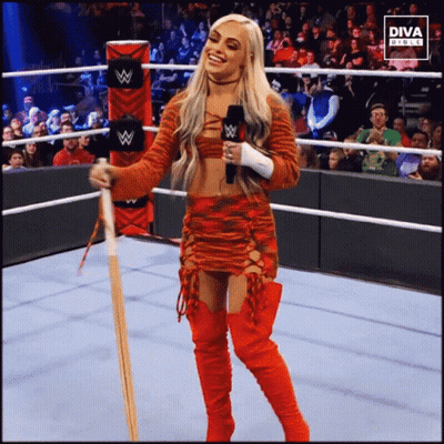A Woman In A Wrestling Ring Holding A Microphone And A Bat With The Diva Press Logo Behind Her GIF