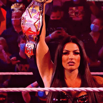 A Woman In A Wrestling Ring Holds A Championship Belt Over Her Head GIF